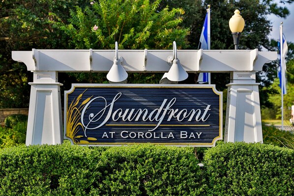 A sign for Soundfront at Corollla Bay, featuring a classic design with a dark background and gold accents.