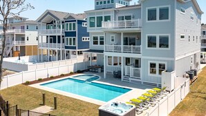 A multi-story residential building with a swimming pool, outdoor seating, and a hot tub. - Pier, Pool, Sunsets • Luxe Soundfront Retreat (Corolla)