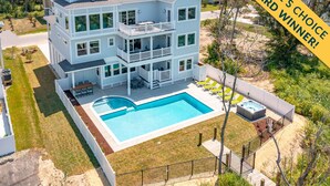 A large, multi-story house with a swimming pool and outdoor seating area. - Pier, Pool, Sunsets • Luxe Soundfront Retreat (Corolla)