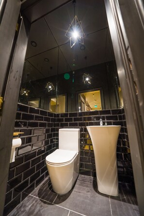 A modern bathroom with black tiled walls, a white toilet, and a white sink. - Leo Boutique Rooms - Adults Only (Budapest)