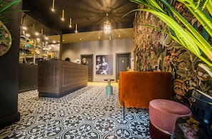 A lobby with patterned flooring, a reception desk, a plush seating area, and a decorative wall. - Leo Boutique Rooms - Adults Only (Budapest)