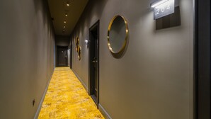 A hallway with a yellow patterned carpet, a number sign '204' on the wall, and circular wall decorations. - Leo Boutique Rooms - Adults Only (Budapest)