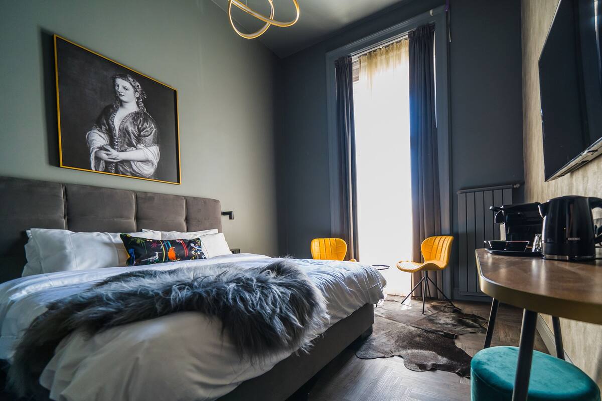 A modern hotel room with a large bed, a coffee table, and a seating area.