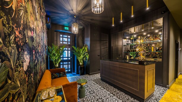 A bar area with a patterned floor, a counter with various items, and a mural with plant and animal illustrations. - Leo Boutique Rooms - Adults Only (Budapest)