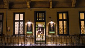 A hotel facade with ornate iron railings, large windows with geometric patterns, and illuminated signs for the Leo Boutique Hotel. - Leo Boutique Rooms - Adults Only (Budapest)
