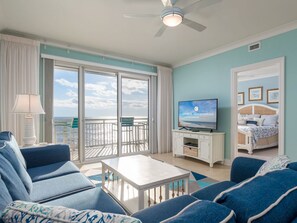 Ein geräumiges Wohnzimmer mit Balkon, Fernseher und Bett mit Blick.
