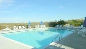 Piscina com espreguiçadeiras e guarda-sóis.