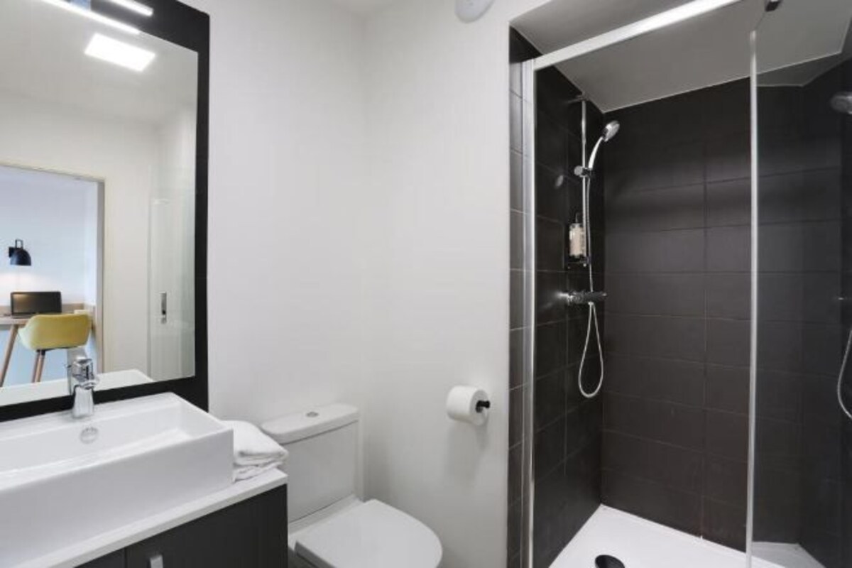 A modern bathroom with a white sink, toilet, and a glass-enclosed shower area.