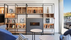 Una sala de estar moderna con chimenea, estanterías de madera y un amplio ventanal que ofrece vistas al exterior.