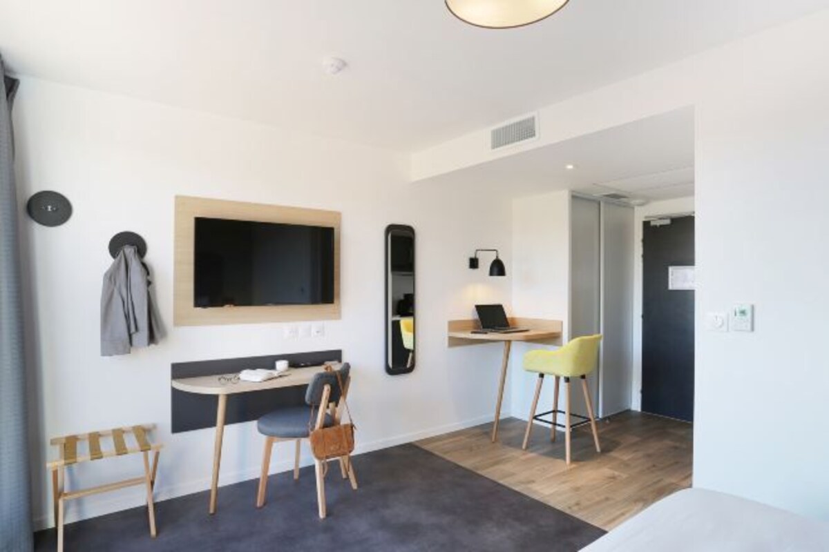 A modern room with a desk, chair, and a television mounted on the wall.