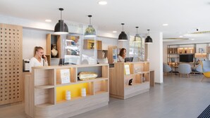 Un área de recepción moderna con mostradores de madera, iluminación colgante y un diseño limpio y minimalista.