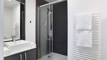 A modern bathroom with a glass-enclosed shower, a white sink, and a towel rack.