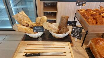 A bakery display with various types of bread and pastries, including labels for 'Pain blanc' and 'Pain au four'.