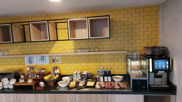 Un buffet de petit-déjeuner proposant une variété d’aliments, une machine à café et un distributeur de boissons.