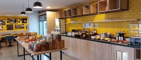 Un bufé de desayuno con diferentes opciones de comida, una estación de café y zonas de estar.