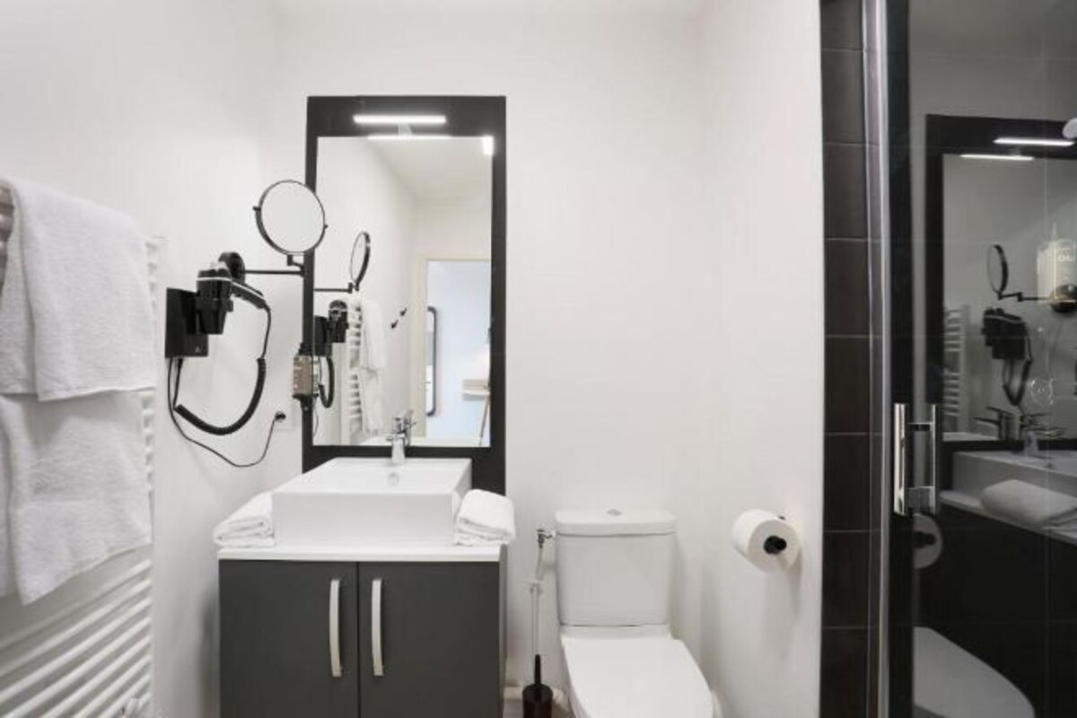 Un baño moderno con un lavabo blanco, muebles oscuros, un inodoro y un espejo.