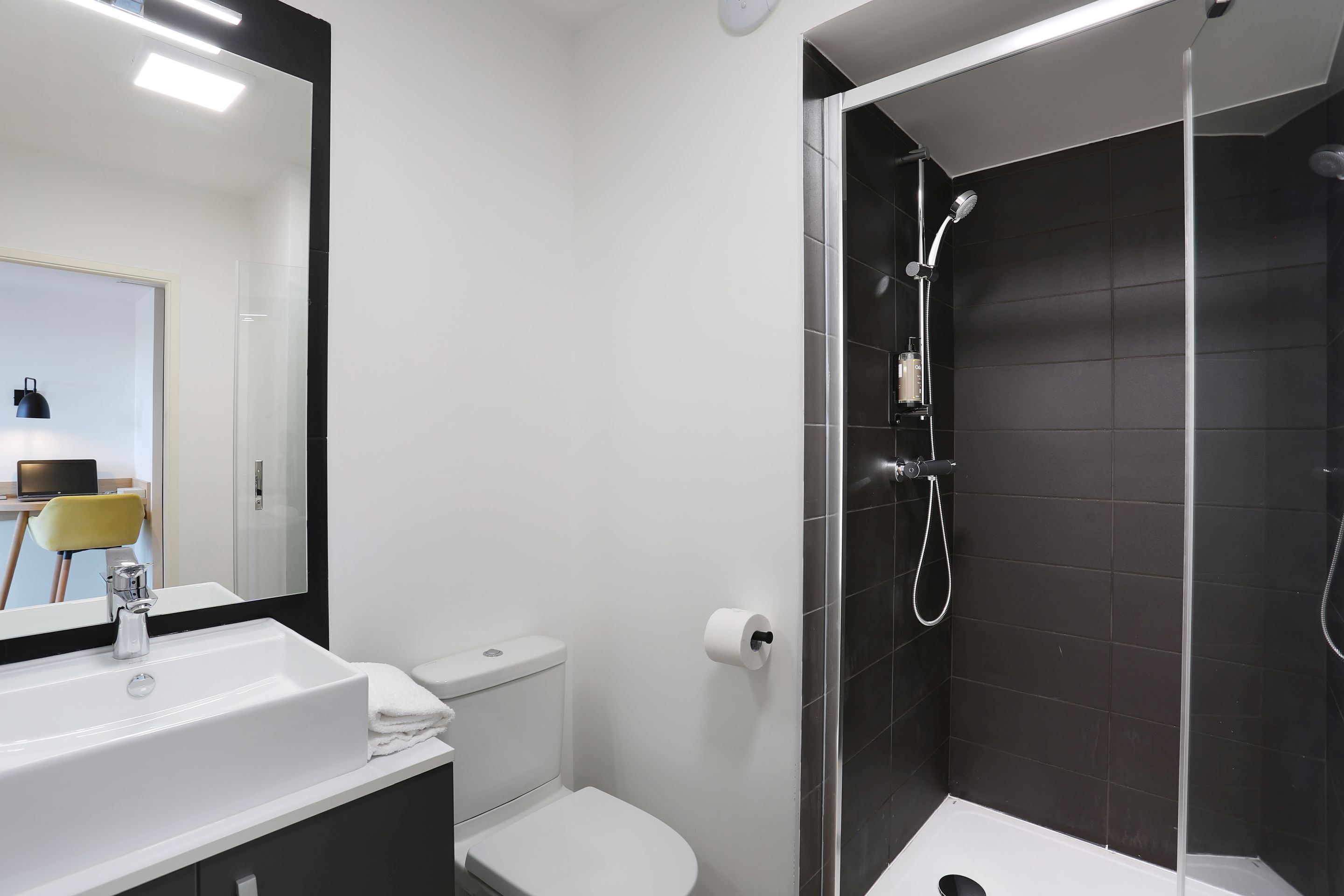 A modern bathroom with a white sink, toilet, and shower.