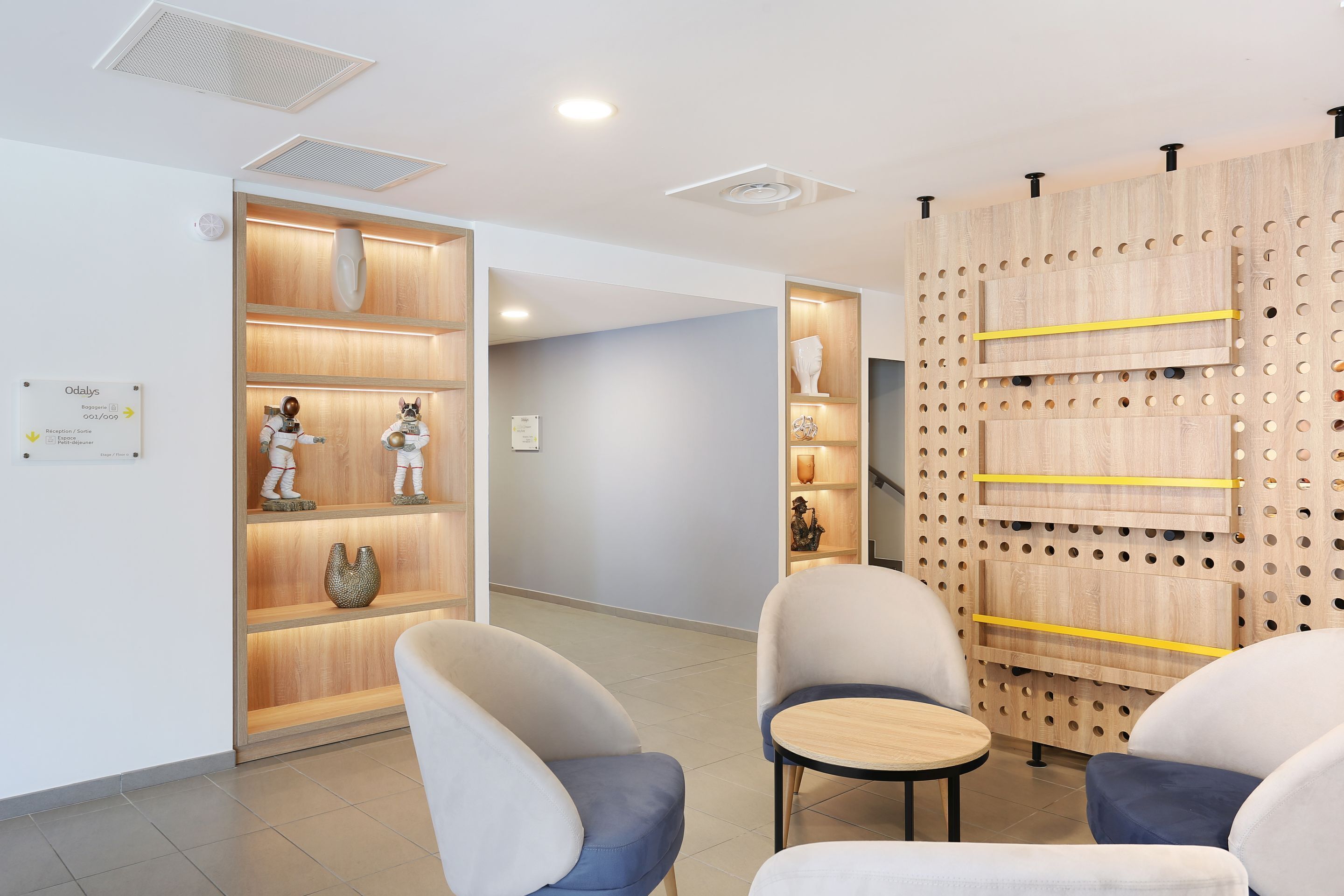 A modern interior with a reception desk, seating area, and wooden shelving with decorative items.