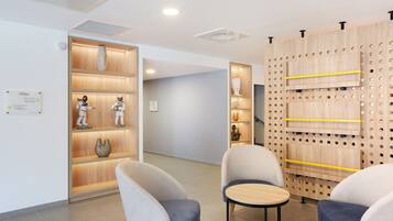 A modern interior with a reception desk, seating area, and wooden shelving with decorative items.