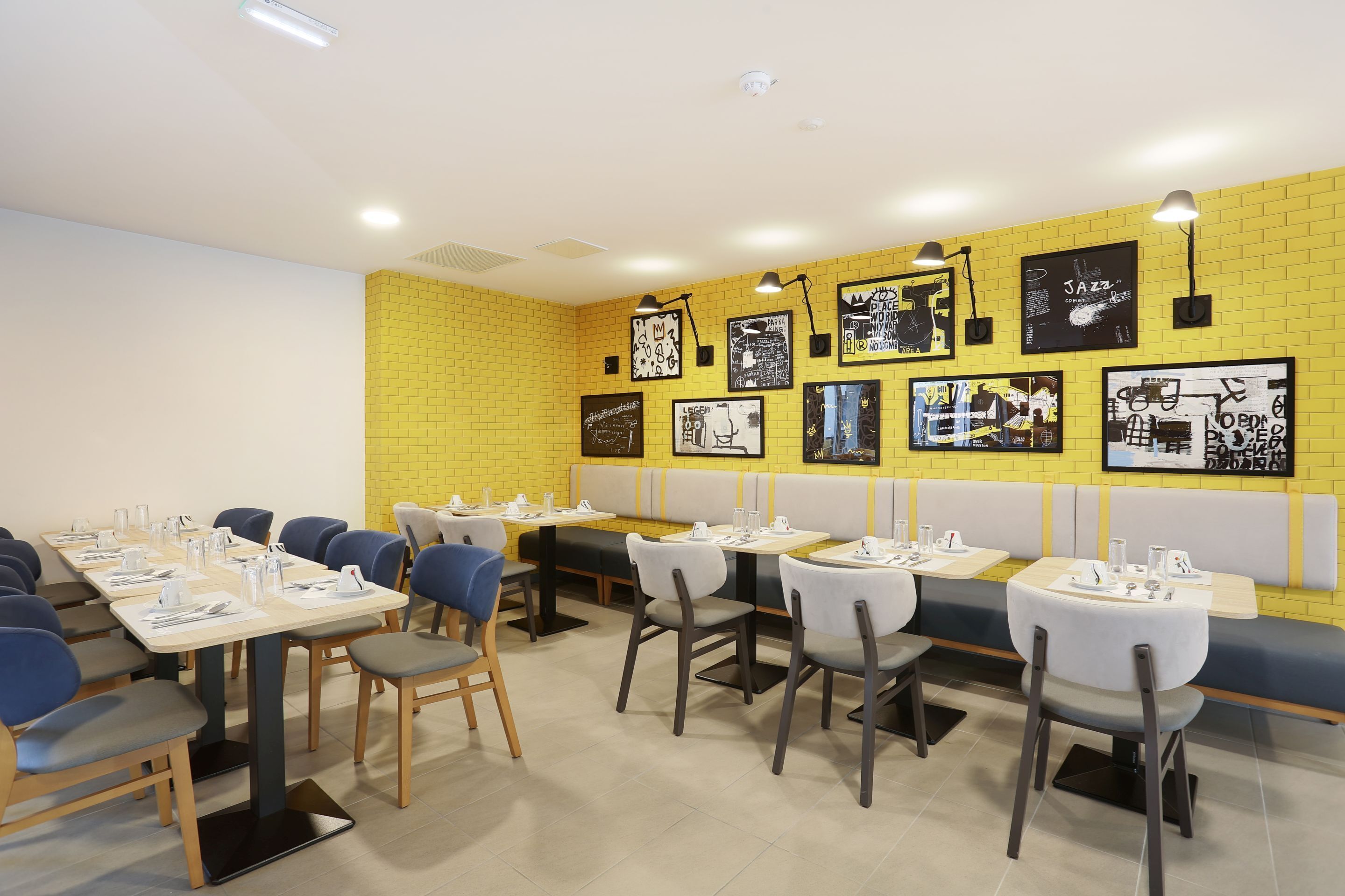 A restaurant with yellow brick walls, multiple tables and booths, and artwork on the walls.