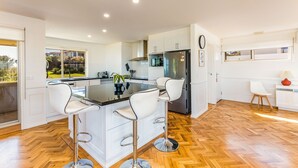 Een moderne keuken met een centraal eiland, witte kasten en een visgraat houten vloer.