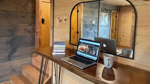Ein Holzblockhaus-Interieur mit einem Laptop auf einem Schreibtisch, einer Tasse und einem Stapel Bücher.
