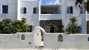 A white building with a stone facade, arched windows, and a gate. - Santa Flora 3 bedroom House (Paros)