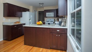 A modern kitchen with dark wood cabinets, a white refrigerator, a microwave, and a large window.