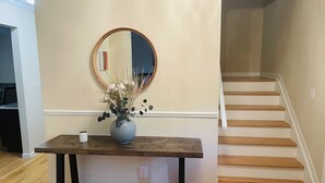 A wooden table with a vase of flowers and a mirror on the wall.