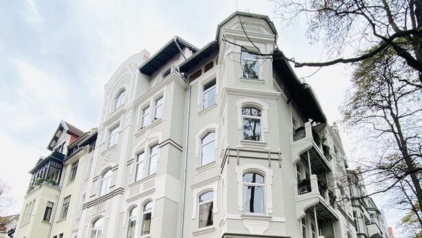 A multi-story residential building with a symmetrical facade, large windows, and a brick base. - Quite, artsy apartment in a central location (Hannover)