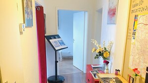 A hallway with a wooden floor, a black and white rug, a desk with a vase of flowers, and a map on the wall. - Quite, artsy apartment in a central location (Hannover)