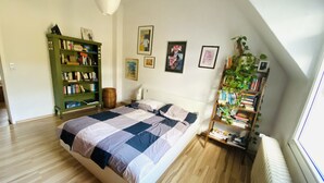 A bedroom with a bed, a green bookshelf, and a radiator. - Quite, artsy apartment in a central location (Hannover)