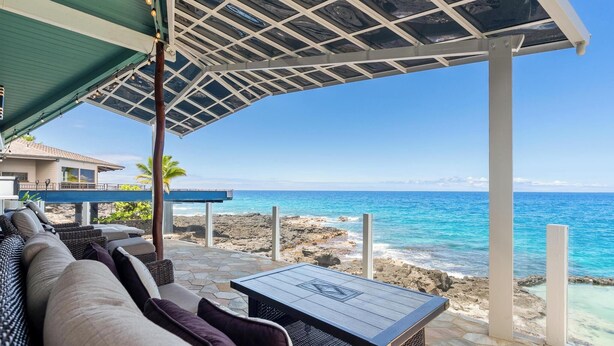 A covered outdoor seating area with a view of the ocean.