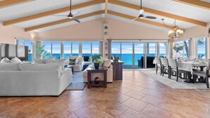 A spacious living area with a high ceiling, large windows, and a view of the ocean.