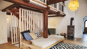 Una camera da letto rustica con un letto di legno, un tappeto decorato, un camino e una scala.