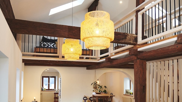 Spazioso loft con travi a vista in legno, un letto a soppalco, un'area pranzo e una scala.