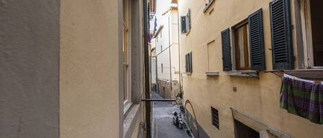 A narrow alleyway with buildings on either side, a motorcycle parked on the right, and laundry hanging on a line.