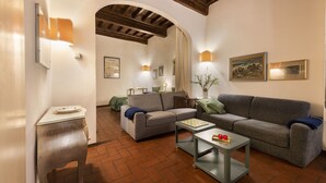 A cozy living room with a fireplace, a sofa, a coffee table, and a dining table. - Pitti Studio by Mmega (Florence)
