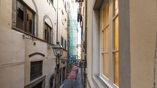 A narrow alleyway with buildings on either side, a metal gate, and a street lamp. - Pitti Studio by Mmega (Florence)