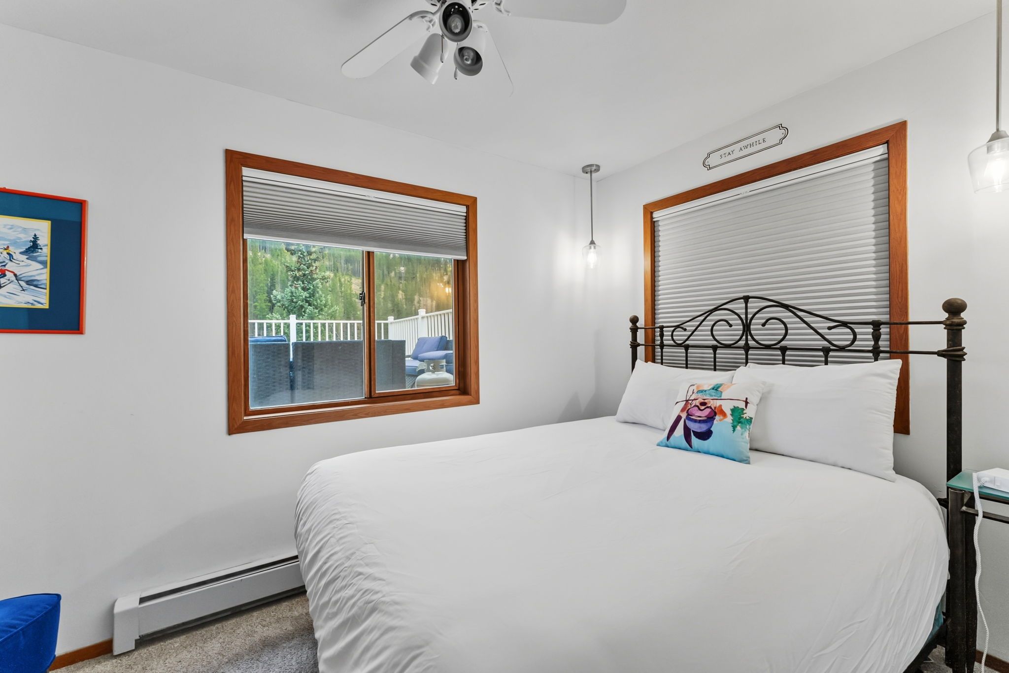 A bedroom with a bed, a ceiling fan, a window with blinds, and a sign that says "STAY AWAY".