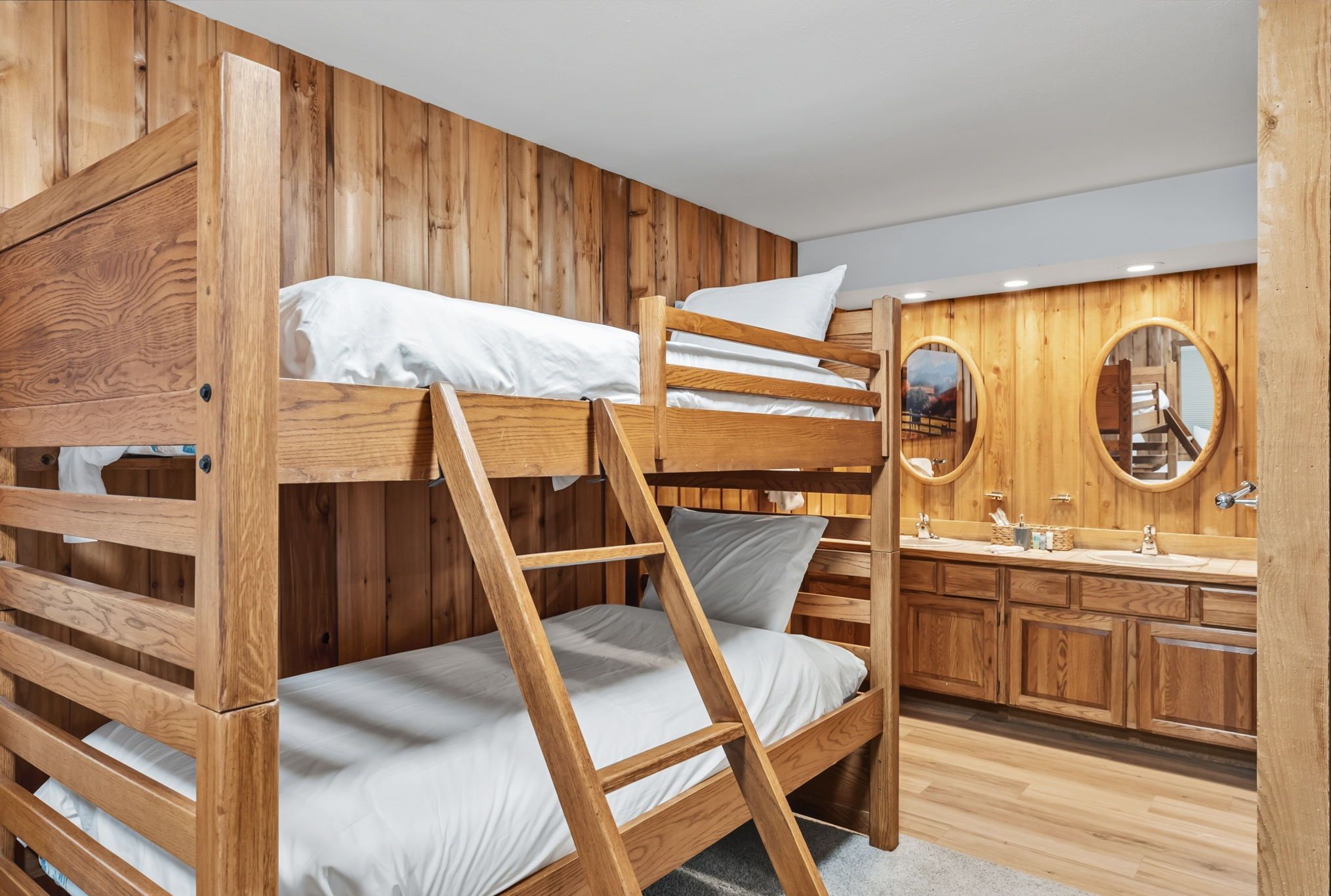 Dormitorio con literas, paredes de madera y tocador de madera con espejo.