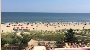 Une plage dotée de nombreux parasols et de chaises longues, d’une clôture en bois et offrant une vue dégagée sur l’océan.