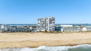 Un hotel frente al mar con varios pisos y una playa arenosa al frente.