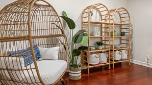 Ein Zimmer mit einem Korbstuhl, einer Holzeinrichtungsregal und einem Blumentopf.