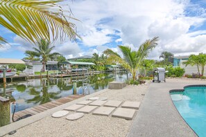 Relax by the tranquil pool, surrounded by lush greenery and a dock area perfect for boating.