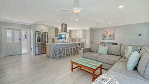 Eine moderne Küche mit Kochinsel, eine Essecke mit einer Couch und ein Wohnzimmer mit Couchtisch.