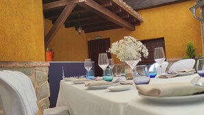 Mesa posta para refeição, com vista para um edifício amarelo e teto de madeira.