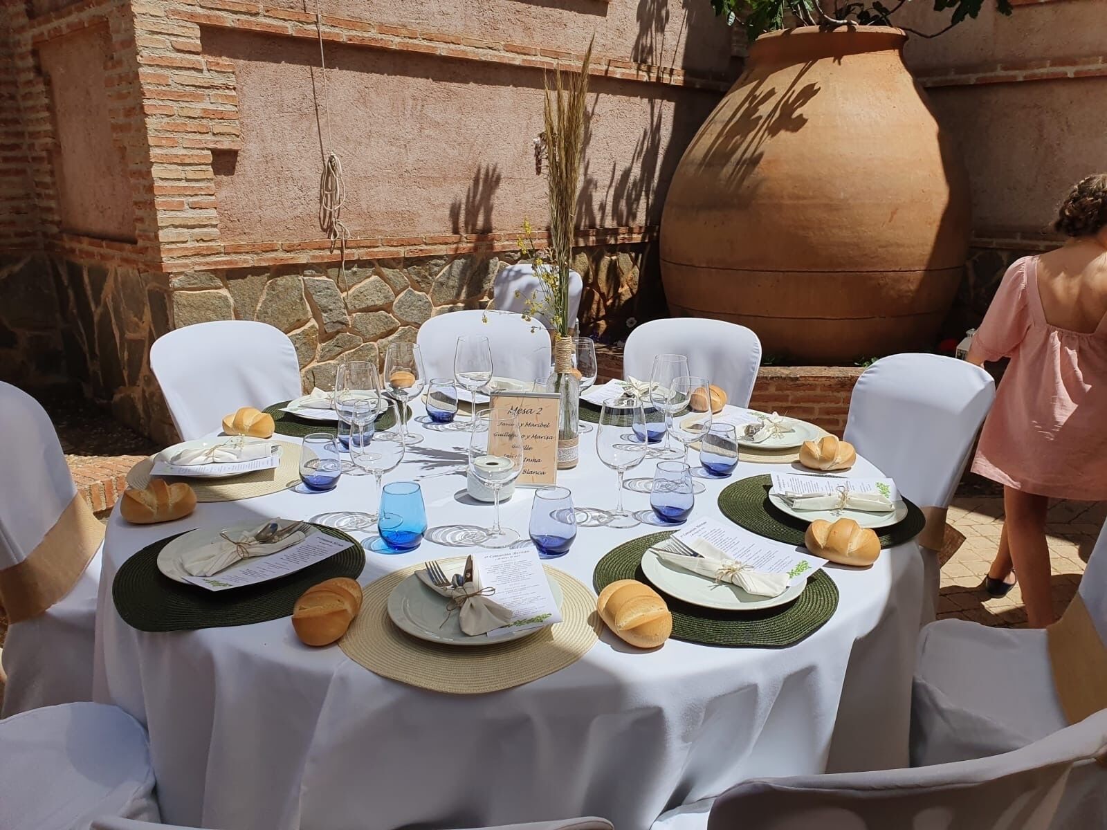 An outdoor dining setup with white tablecloths, round tables, and chairs.