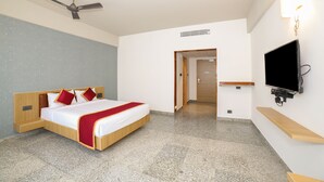 Hotelkamer met een bed, een plafondventilator, een televisie en een deur naar een andere kamer.