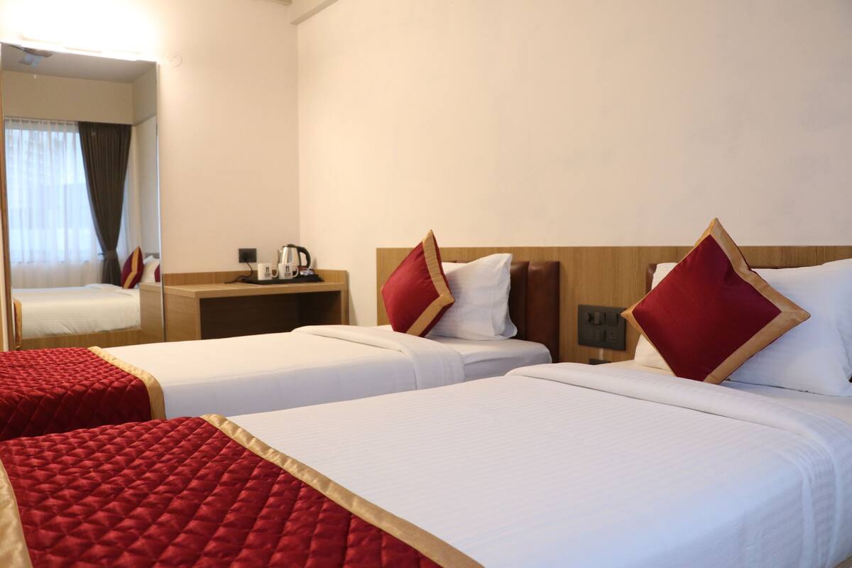 A hotel room with two beds, a wooden headboard, a nightstand with a coffee maker, and a mirror.
